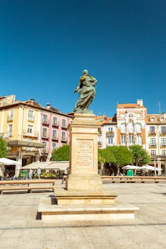 Sunlit view of Carlos II monument in vibrant Burgos city square, Spain.