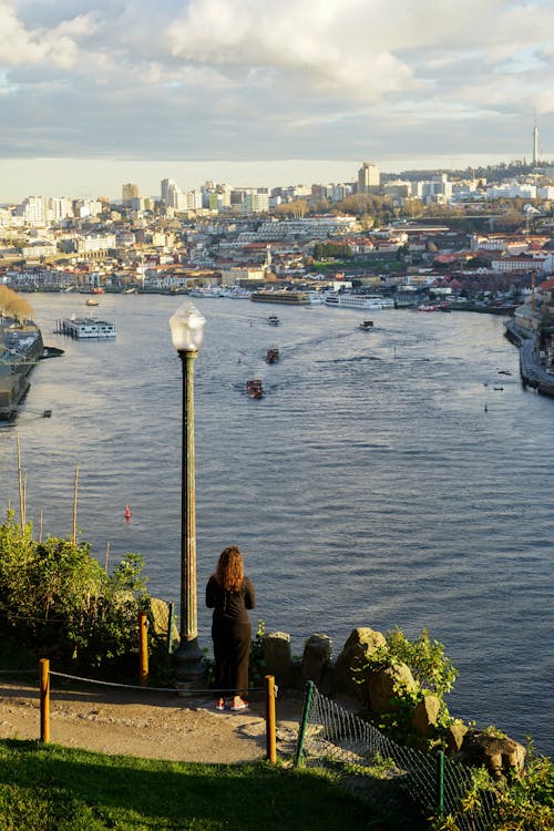 Woman Standing on Hill over River in City