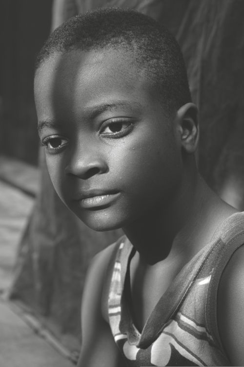 Free A striking black and white portrait capturing the solemn expression of a young boy. Stock Photo