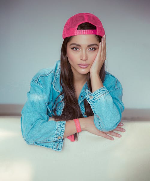 A young woman wearing a pink hat and denim jacket