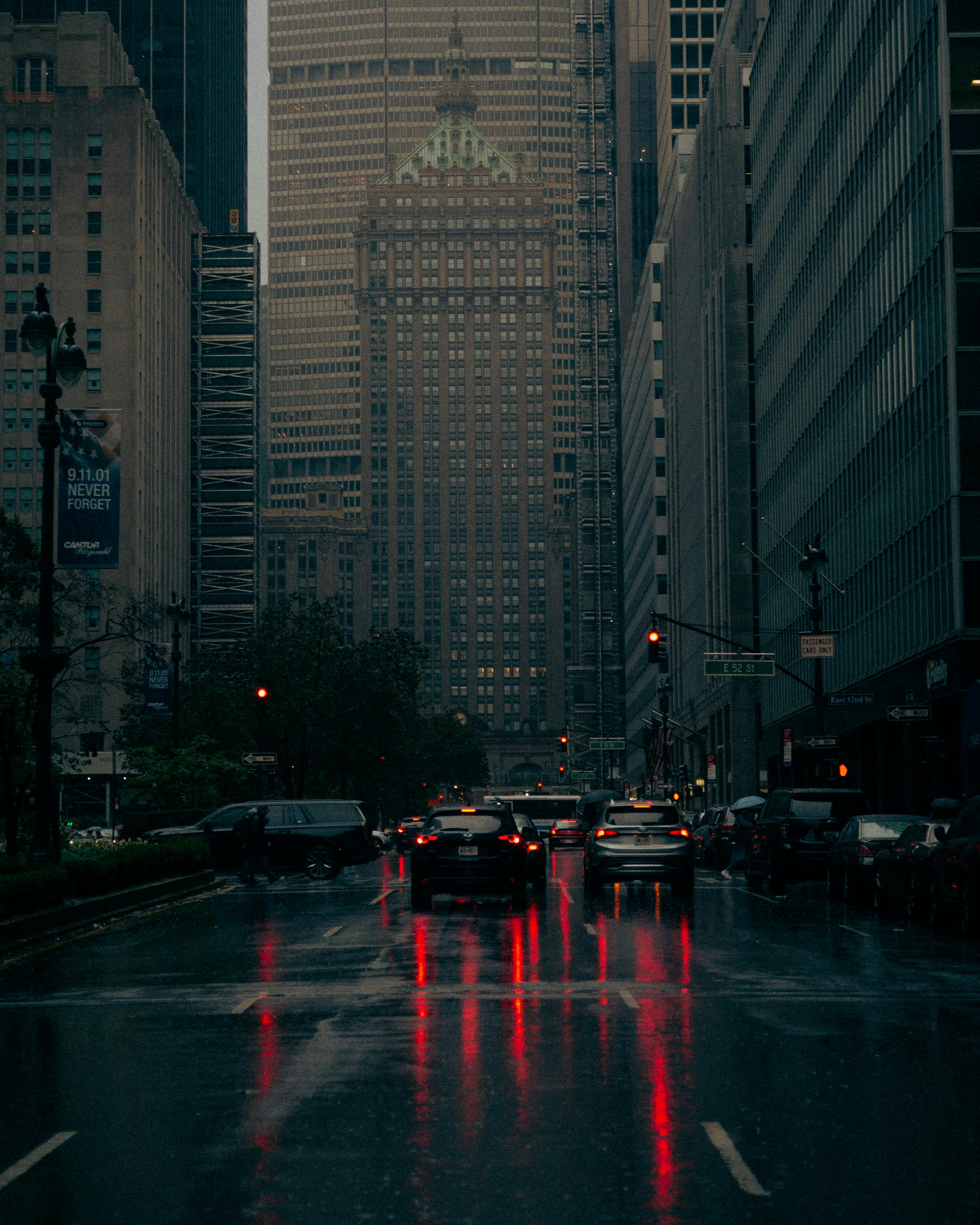 Nighttime view of a rainy street in New York City, reflections and city lights creating a moody atmosphere.