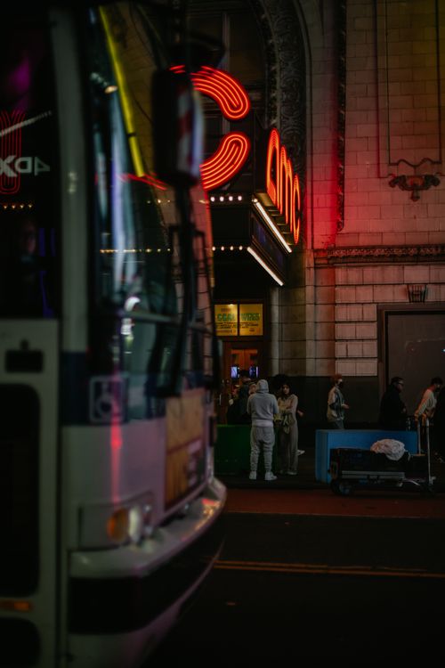 Free A bustling city street at night with a bus and illuminated theater sign. Stock Photo