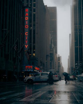 Moody cityscape of Radio City Music Hall at night with rain in New York City.