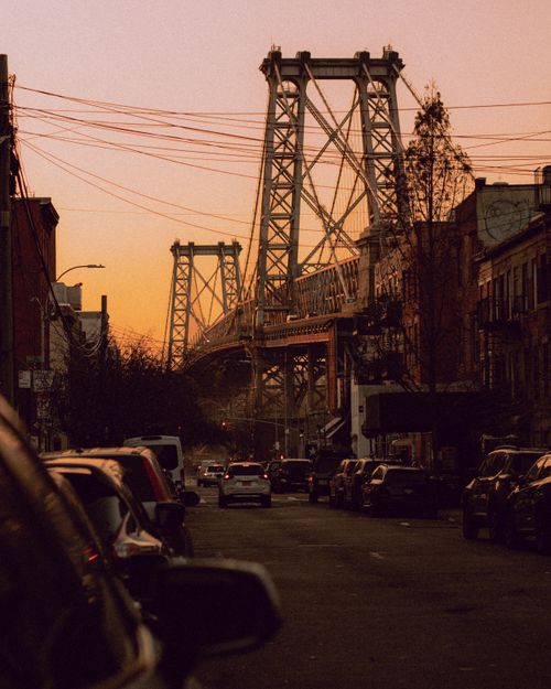 Free A scenic view of a city bridge with urban architecture during sunset, featuring cars and bustling street life. Stock Photo