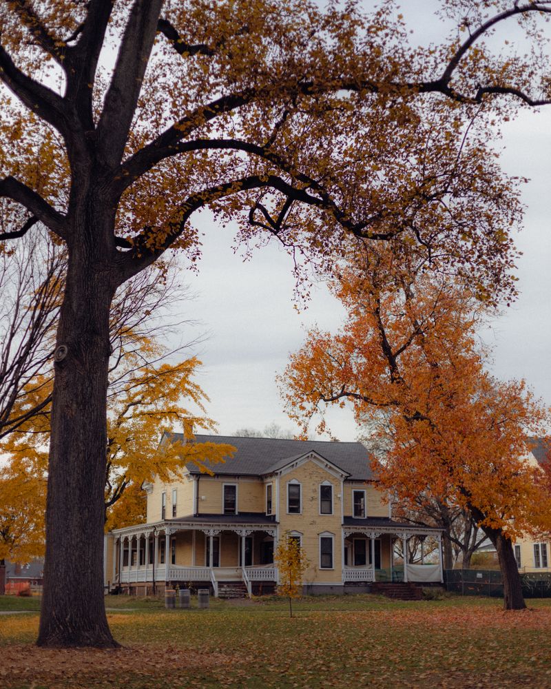 Victorian house with a covered porch under mature trees