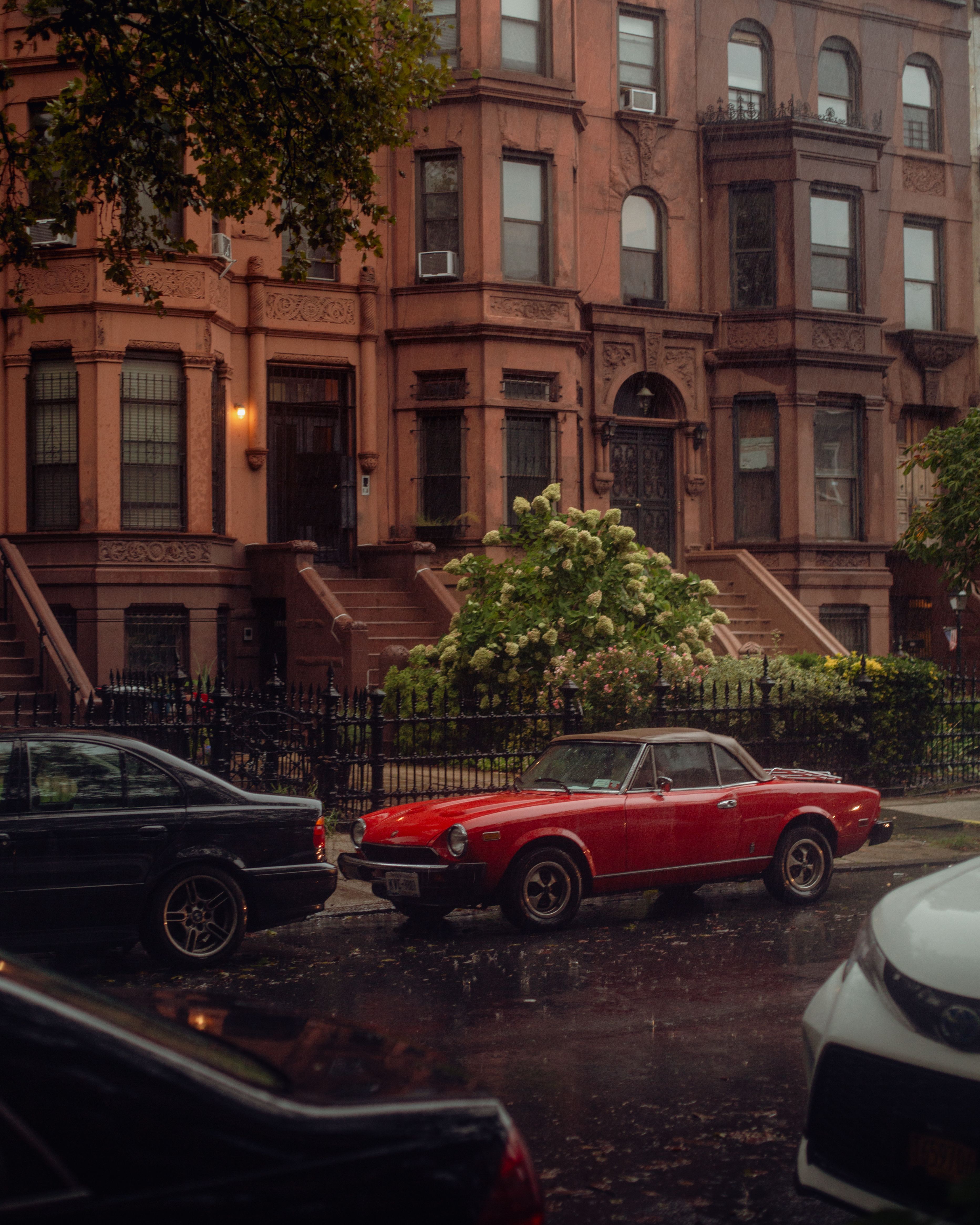 A car parked in front of a row of brownstone buildings · Free Stock Photo
