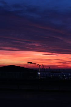 A stunning urban skyline silhouette against a vibrant sunset with deep purple and orange hues.