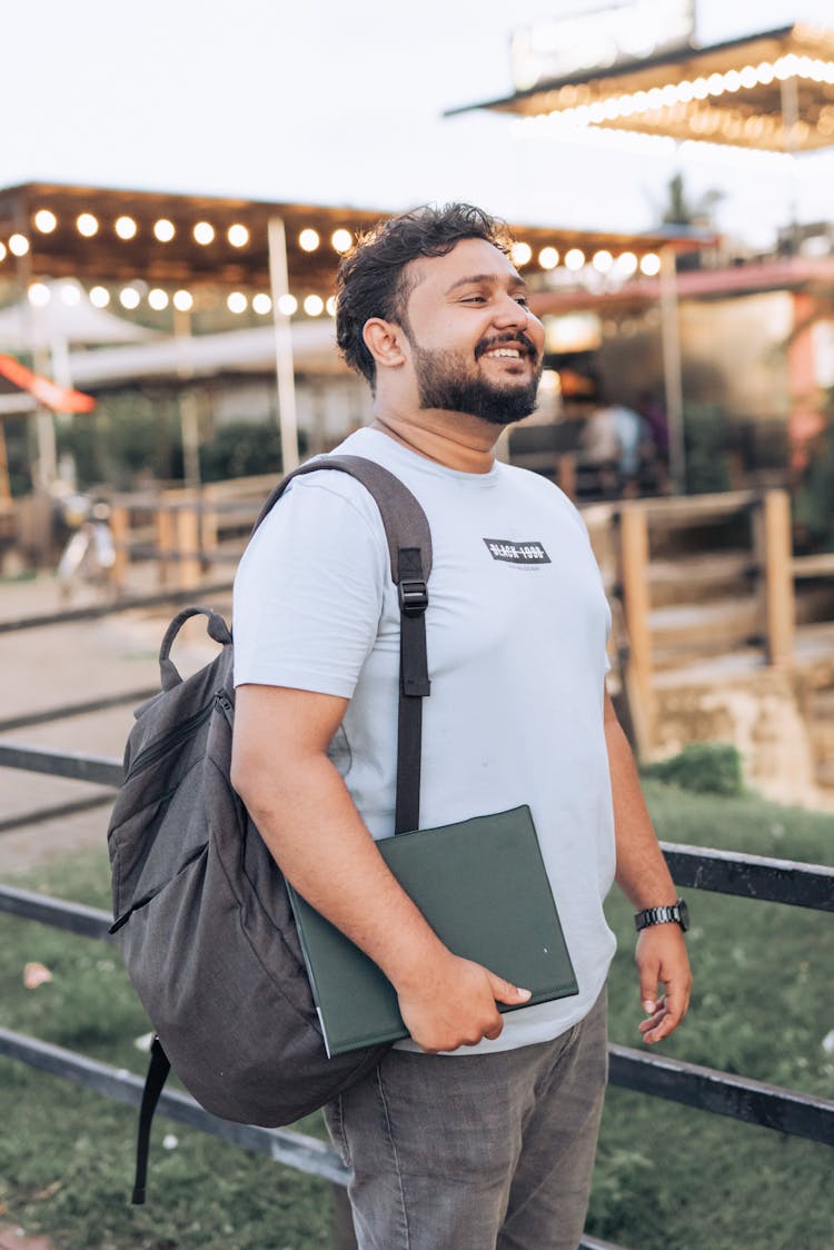 A Bearded Man Holding A Laptop And Smiling 