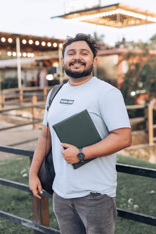 A Bearded Man Holding a Laptop and Smiling 
