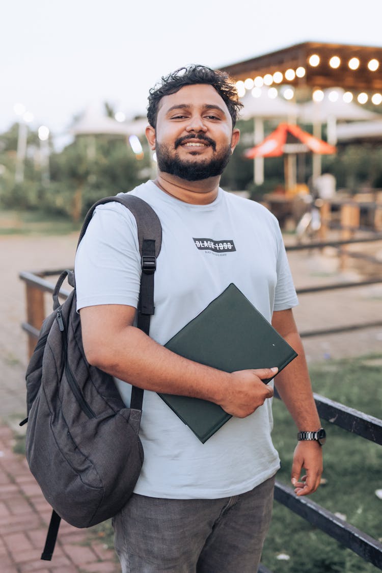 A Bearded Man Holding A Laptop And Smiling 