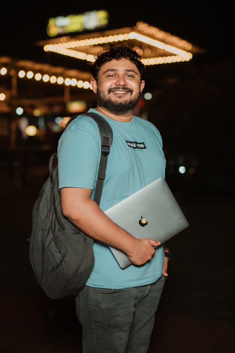 A Bearded Man Holding A Laptop And Smiling 