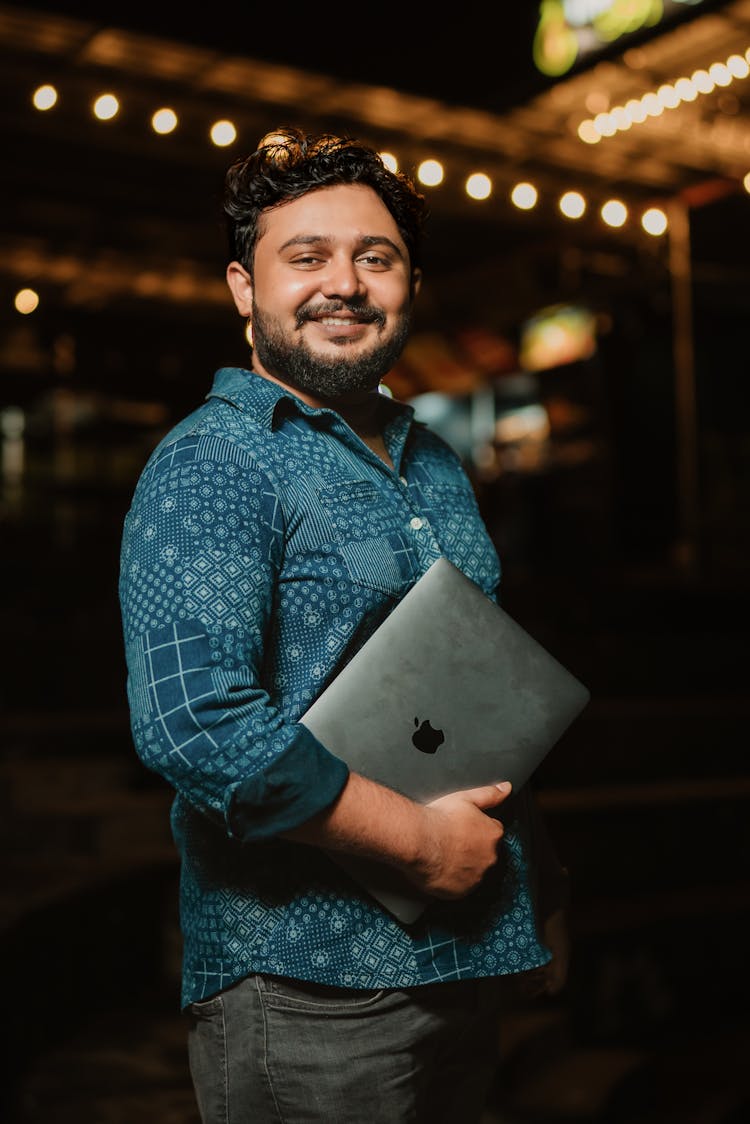 A Bearded Man Holding A Laptop And Smiling 