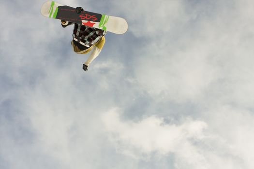 Snowboarder catches air with dynamic jump against a cloudy sky backdrop.