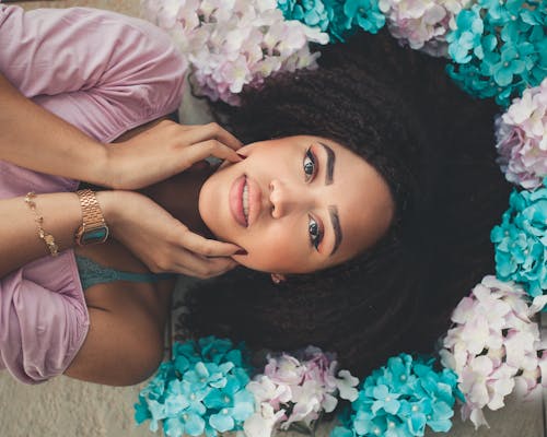 그녀의 머리 주위에 흰색과 청록색 종이 꽃과 흰색 표면에 누워있는 여자