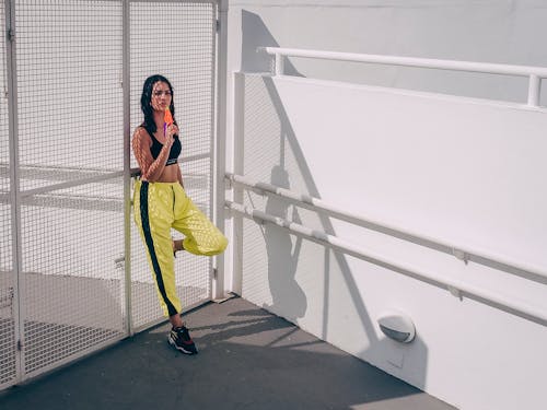 Woman Leaning On Mesh Gate While Holding Ice Pop