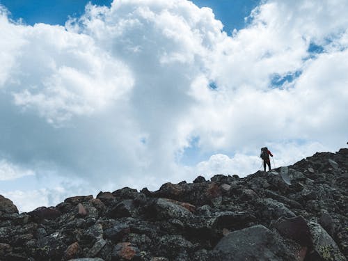 Person Hiking on Rocks in Mountains