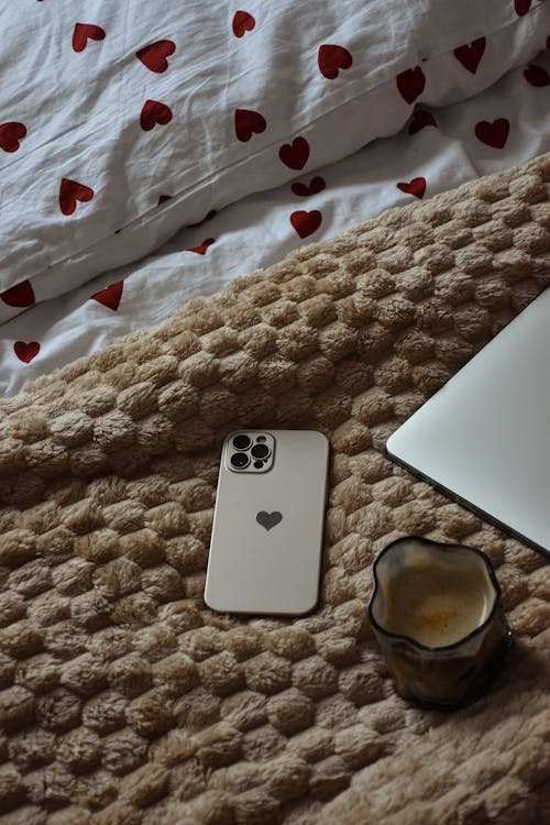 A Smartphone and a Coffee on a Bed
