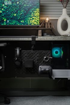 Vertical shot of gaming setup with monitor, controller, and tech accessories on desk.