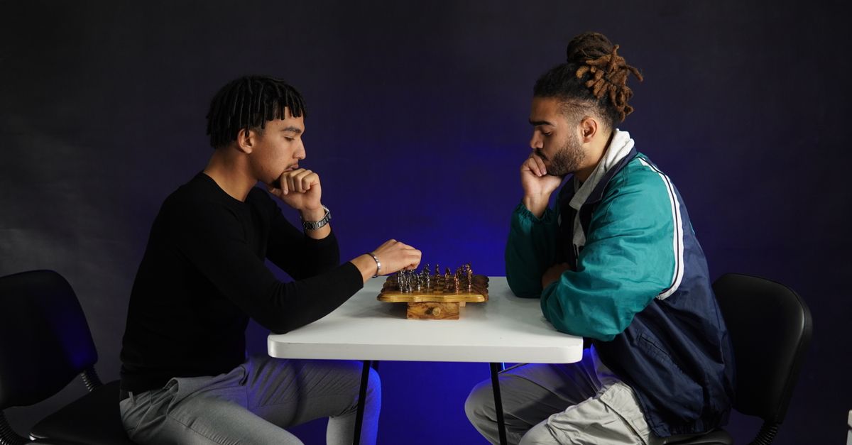 Two adults deeply engaged in a strategic chess match indoors, fostering concentration.