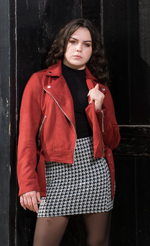 Young Model in a Red Jacket and Checkered Mini Skirt Posing in the Doorway