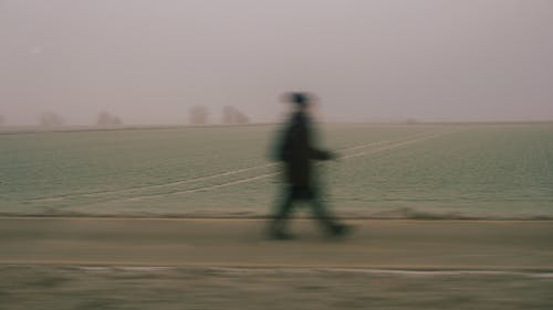 Silhouette of a Person Walking Along a Country Road