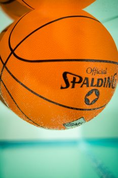 Vibrant orange basketball with branding against a blue background, showcasing texture and detail.