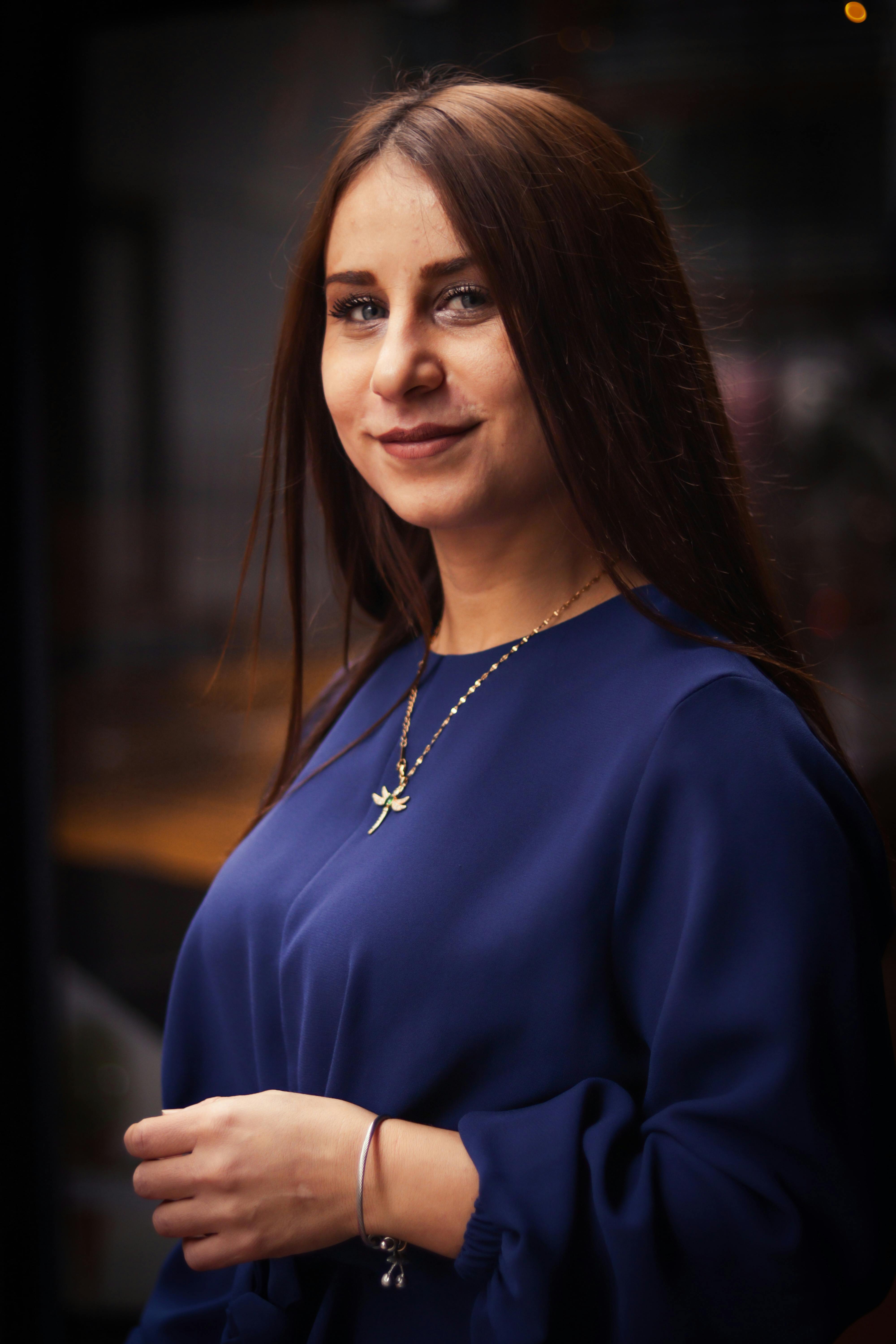Portrait of a smiling woman in a blue outfit, captured indoors with a fashionable and modern style.
