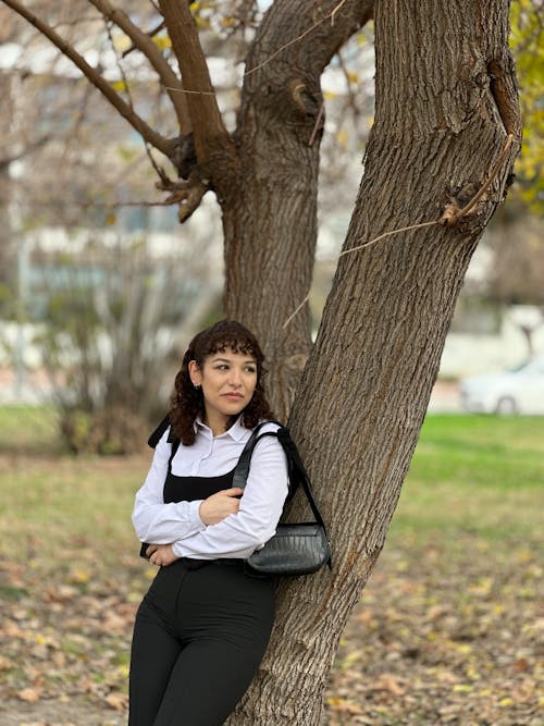 Woman in White Shirt Standing by Tree at Park