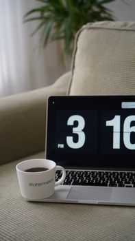 A cozy home workspace with a cup of coffee and a laptop showing 3:16 PM.