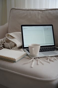 A comfortable home office setup with a laptop and coffee mug on a cozy couch, perfect for productivity.