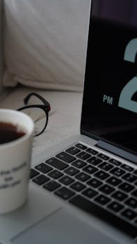 Cozy home office scene with coffee, laptop, and eyeglasses. Perfect for remote work inspiration.