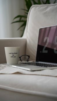 A cozy home workspace setup with a laptop and coffee cup on a neutral couch, perfect for relaxation.