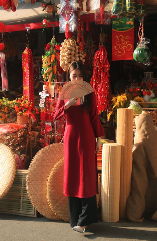 A woman in a red dress is standing in front of a store