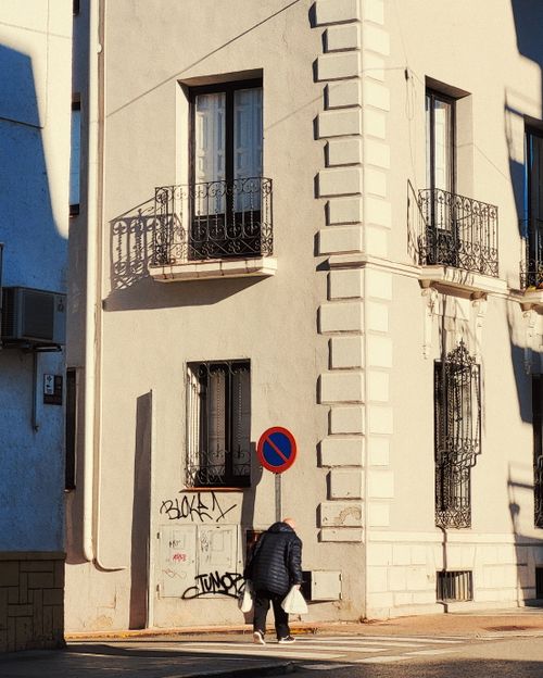 Free A woman walks along a sunlit street in Madrid, capturing urban architecture and daily life. Stock Photo