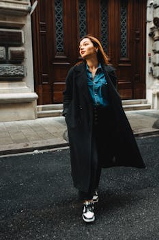 Stylish woman in a black coat walking on city streets with a confident expression.