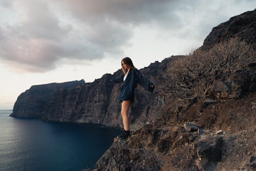 Woman Standing on Rocks on Sea Shore
