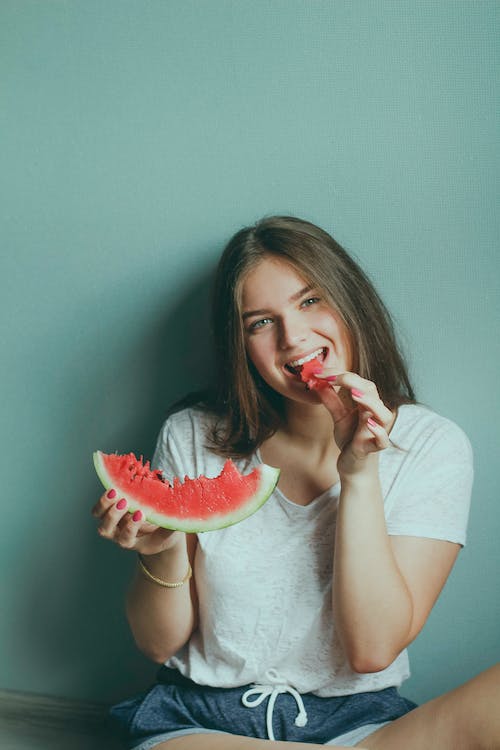 Gratis Wanita Mengenakan Kemeja Putih Makan Semangka Foto Stok