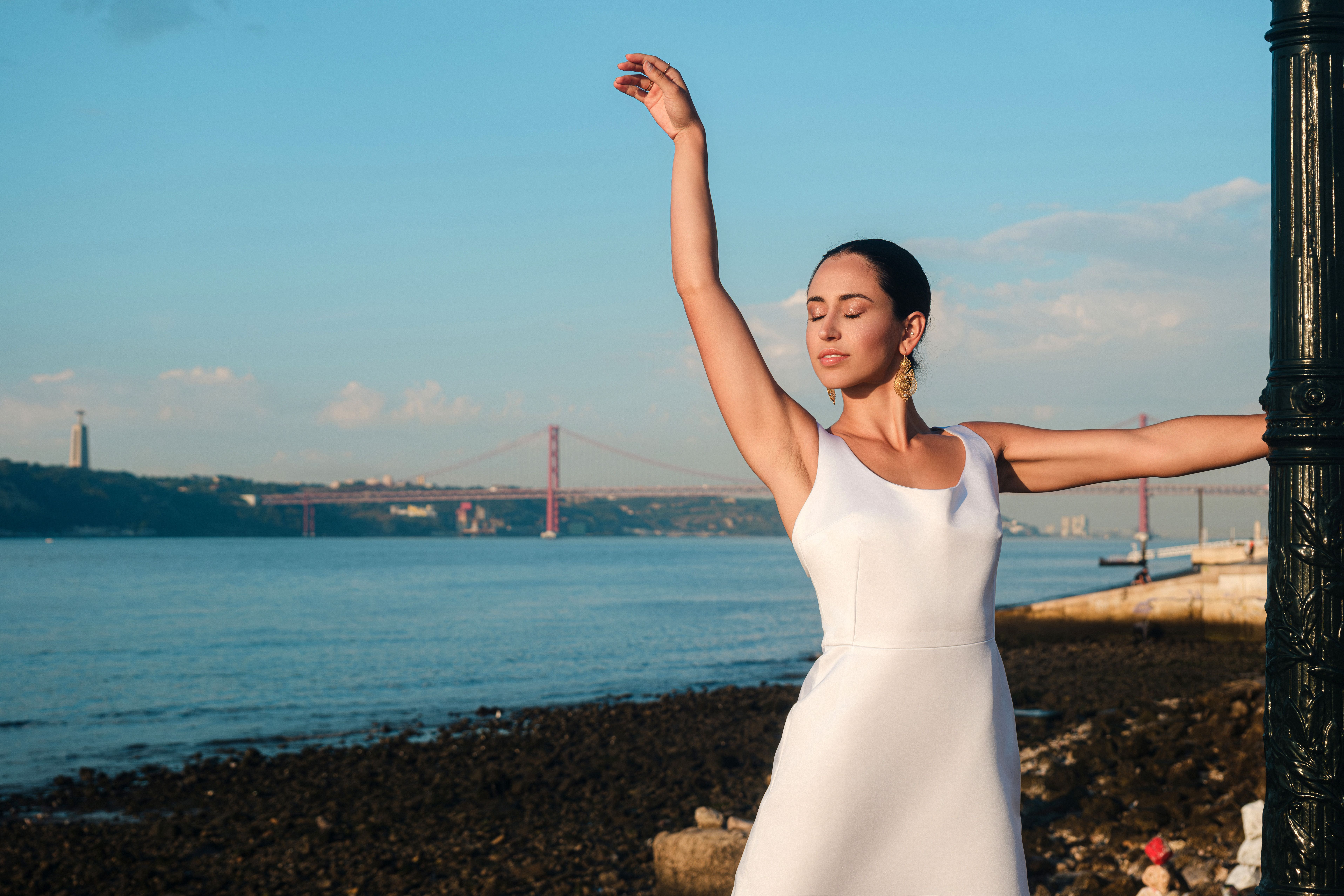 Brunette Woman in White Dress Standing with Arm Raised on Beach · Free ...