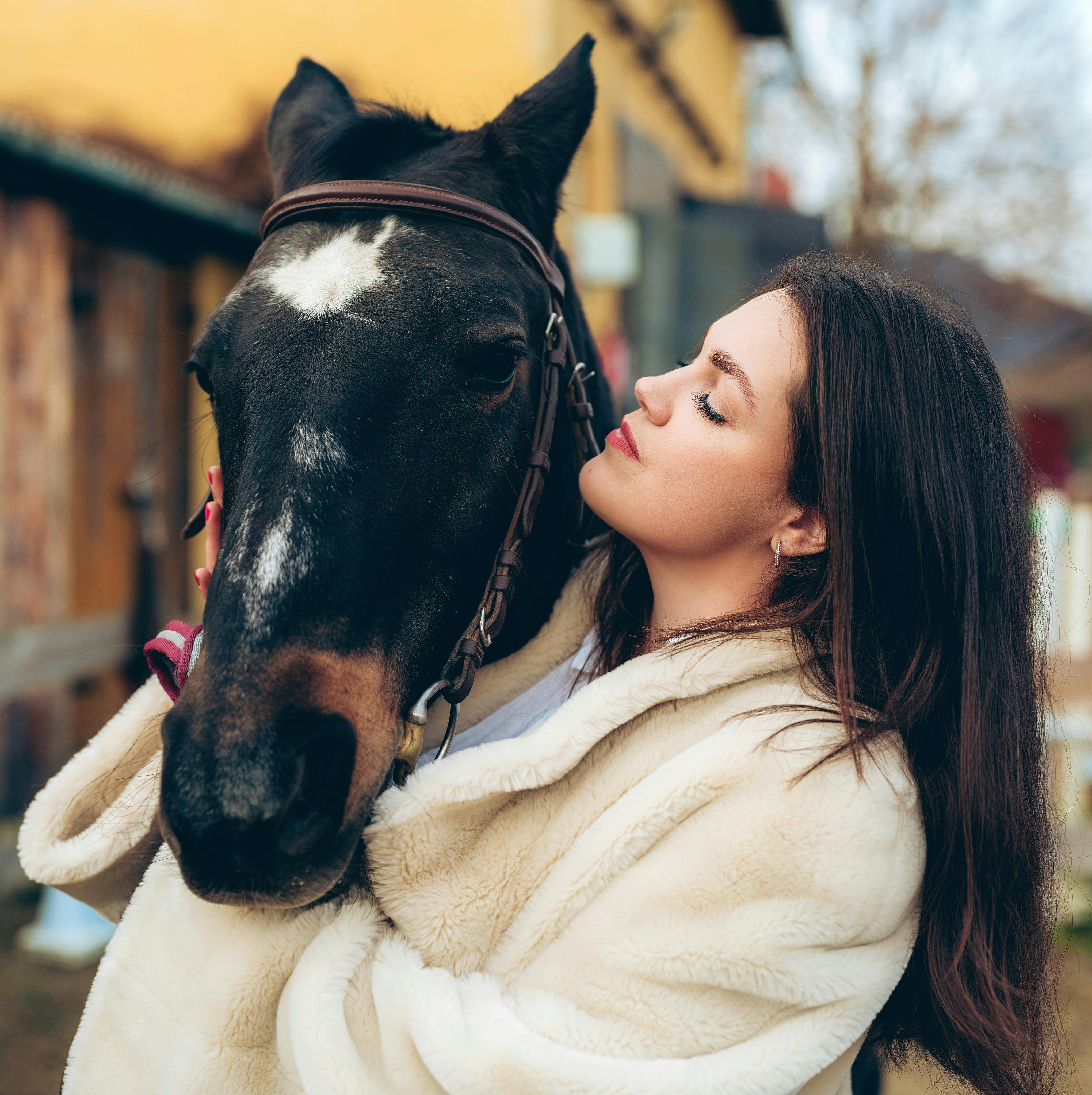 A woman lovingly hugs a horse in a scenic countryside setting in Trenčín, Slovakia.