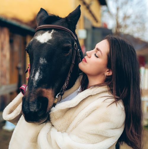 Free A woman lovingly hugs a horse in a scenic countryside setting in Trenčín, Slovakia. Stock Photo