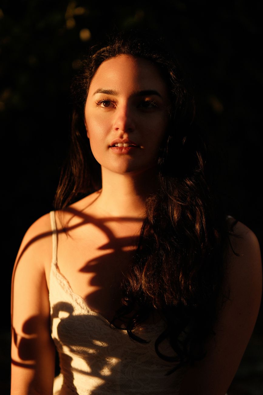 Artistic portrait of a woman in Lisbon with dramatic shadows and warm lighting.