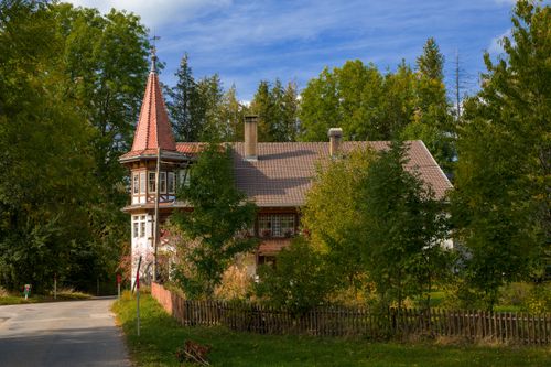 Free A picturesque Swiss house with a tower amidst lush greenery in Le Locle. Stock Photo