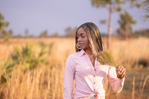 A woman in a pink shirt is standing in a field