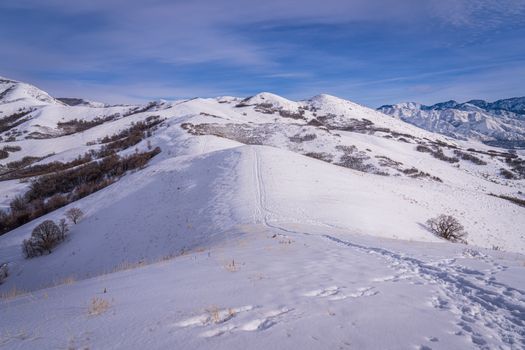 Scenic view of snow-covered hills under a clear blue sky, showcasing winter's beauty.