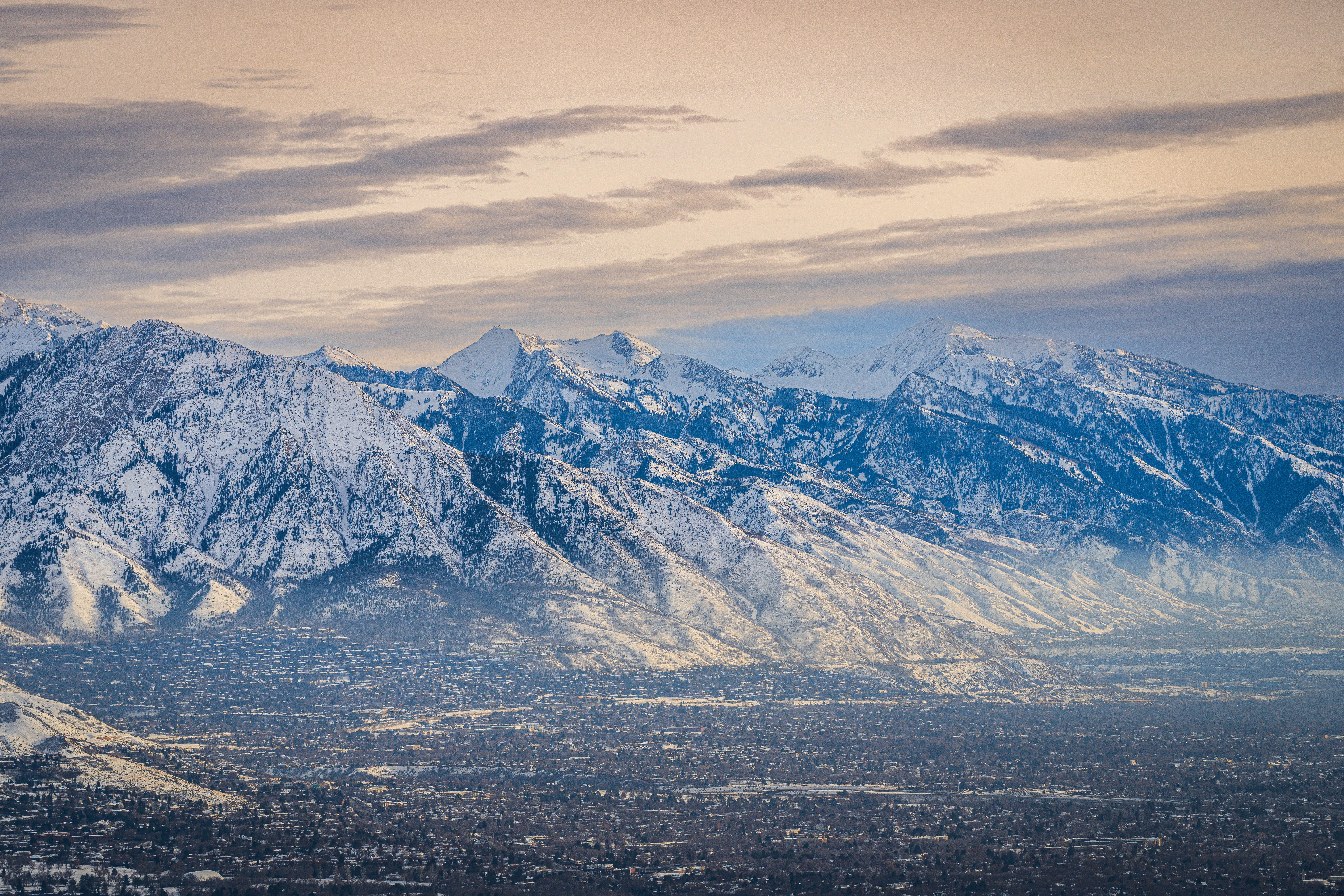 A breathtaking aerial view of a snowy mountain range with a valley below during winter.