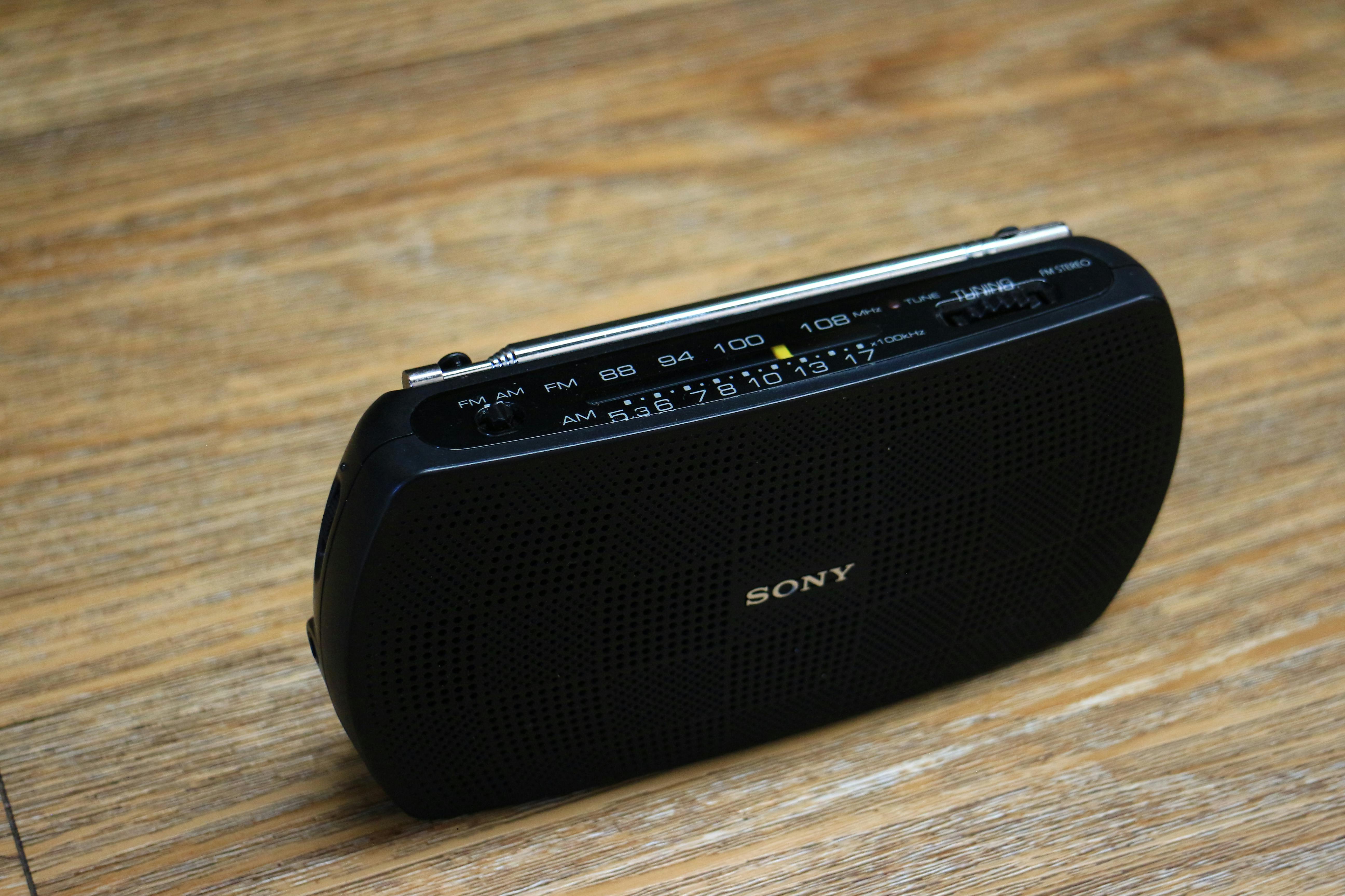 Close-up of a portable black radio on a wooden background, highlighting its design.