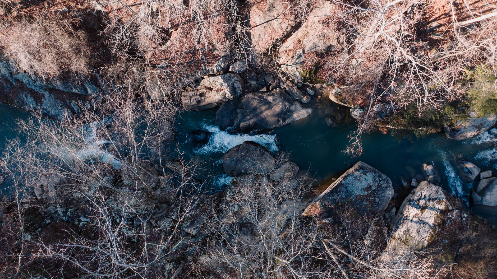 Aerial view of a tranquil stream surrounded by rocks and trees in Gadsden, Alabama.