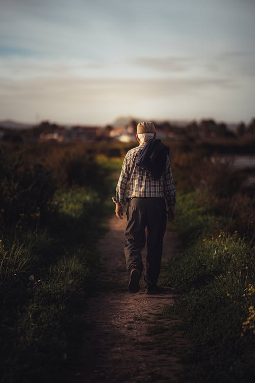 Elderly Man Walking on a Field During Sunset 