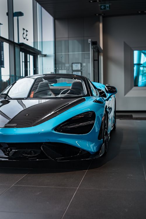 Free High-performance blue supercar on display in a sleek, modern showroom setting. Stock Photo