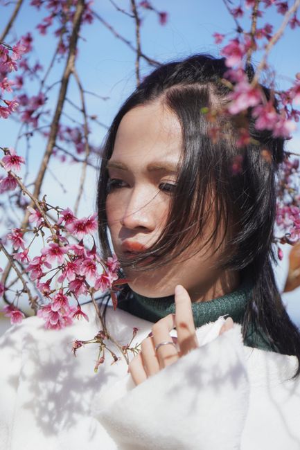 Close-up portrait of a woman surrounded by cherry blossoms, evoking a serene spring mood in Đà Lạt, Vietnam.